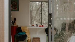 Ein gemütliches Zimmer mit einem Sessel, einem kleinen Tisch und einem Fenster mit Blick auf Bäume.