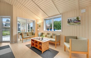 Relax in this open-plan living space with a high ceiling, sofa, and large windows offering garden views.
