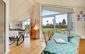 Relax in this inviting room with a view, featuring a dining table, a comfortable rocking chair, and a cozy corner with a lamp.