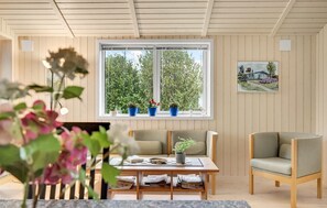 Relax in a serene space with a view of lush greenery, featuring a comfortable seating area and a beautiful framed painting.