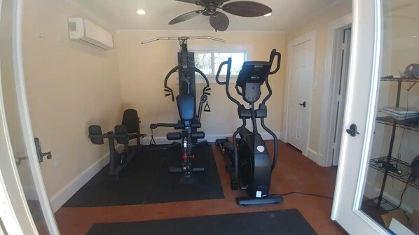 A home gym with two exercise bikes, a bench press, and a squat rack.