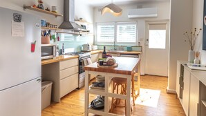 A modern kitchen with wooden countertops, a central island, and a hanging light fixture. - Spacious Two-Bedroom Apartment Near the Heart of Adelaide (Unley Park)