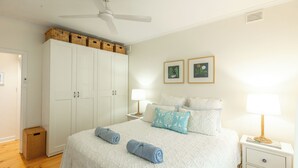 A neatly arranged bedroom with a large bed, a wardrobe, a bedside table with lamps, and a ceiling fan. - Spacious Two-Bedroom Apartment Near the Heart of Adelaide (Unley Park)