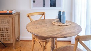 A dining area with a round wooden table, two chairs, a framed picture on the wall, a small cabinet, and two blue vases on the table. - Spacious Two-Bedroom Apartment Near the Heart of Adelaide (Unley Park)