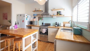 A compact kitchen with a wooden countertop, stainless steel appliances, and a hanging light fixture. - Spacious Two-Bedroom Apartment Near the Heart of Adelaide (Unley Park)
