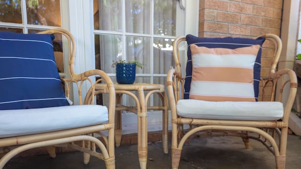 Two wicker chairs with cushions, a small table with a blue vase, and a brick wall. - Spacious Two-Bedroom Apartment Near the Heart of Adelaide (Unley Park)