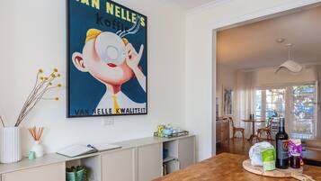 A modern kitchen with a wooden table, a poster on the wall, and a view of the dining area.