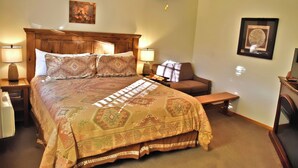 A bedroom with a large bed, two bedside tables with lamps, a ceiling fan, a bench, and a fireplace. - White Cliffs are Truly a Glorious Sight -Pool -Hot Tub-Breakfast-Farm-Zion/Bryce (Mount Carmel)