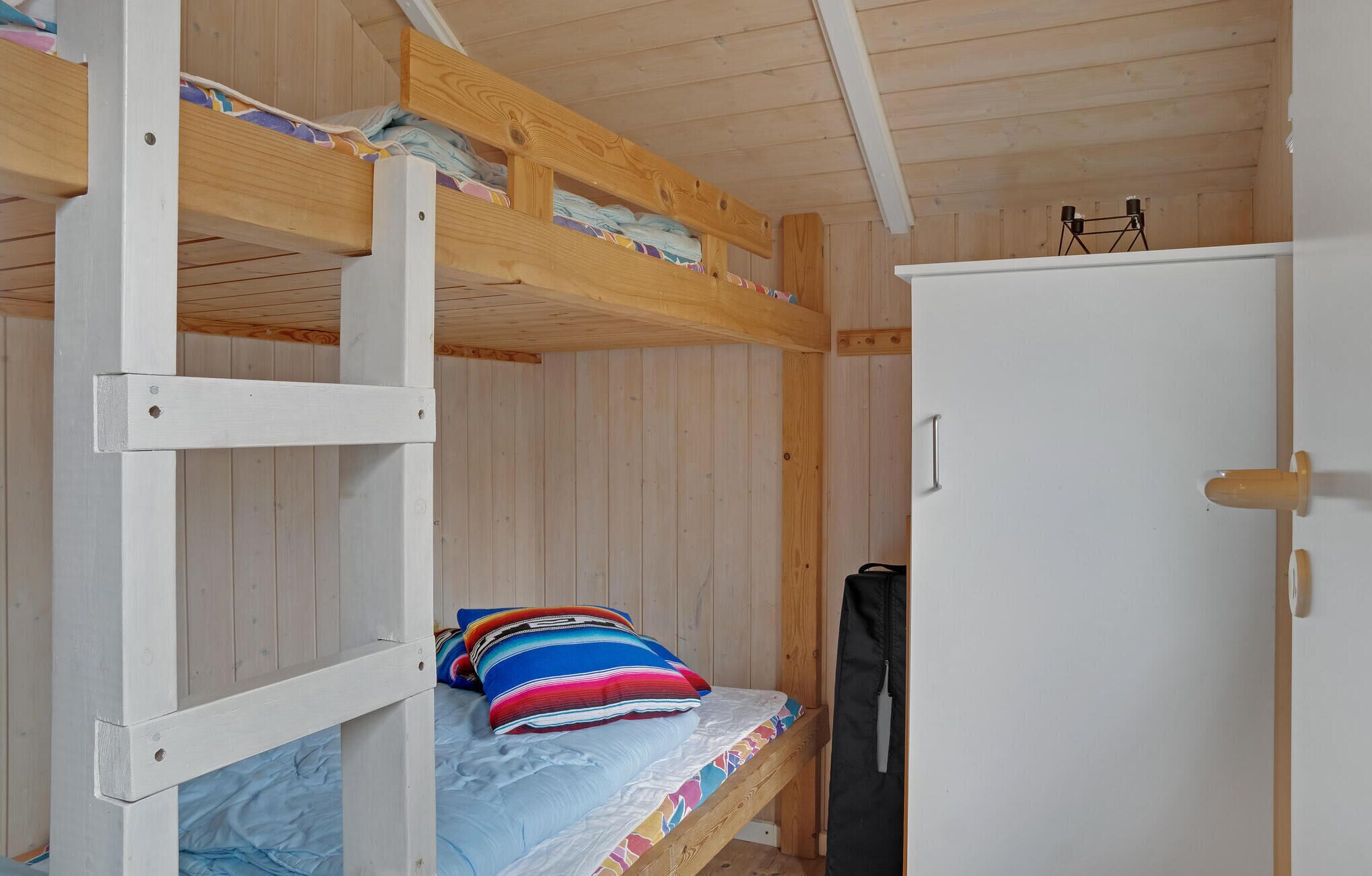 Habitación con literas, una puerta blanca y un armario pequeño.