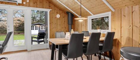 Un intérieur en bois comprenant un coin repas avec une table et des chaises, de grandes fenêtres et un ventilateur de plafond.
