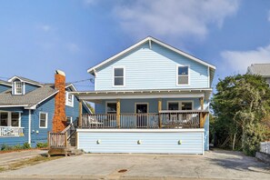A two-story house with a front porch, a garage, and a brick chimney.