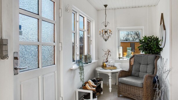 A cozy room with a wicker chair, a small table, and a chandelier. - Lovely home in ålbæk with kitchen (Ålbæk)