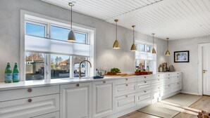 A modern kitchen with white cabinetry, a large window, and pendant lighting. - Lovely home in ålbæk with kitchen (Ålbæk)