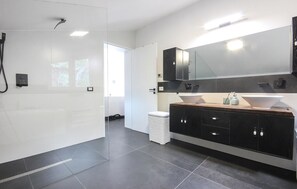 A modern bathroom with a glass shower enclosure, a large mirror, and a dark wooden vanity with a white sink.