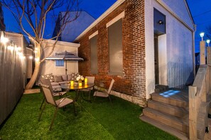A backyard with a wooden deck, a brick wall, and a small table with candles.