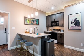 Una cocina moderna con una isla central, taburetes de bar y un refrigerador.