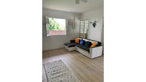 A modern living room with a sectional sofa, a patterned rug, and a decorative wall piece. - Welcome to the heart of my island (Schoelcher)