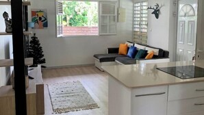 A modern kitchen with a central island, white cabinetry, and a ceiling fan. - Welcome to the heart of my island (Schoelcher)