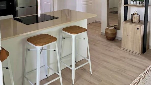 A modern kitchen with a central island, white bar stools, a black refrigerator, and a wooden cabinet with shelves. - Welcome to the heart of my island (Schoelcher)