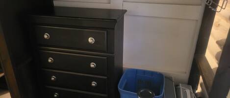 Een zwarte dressoir met vier lades en een blauwe plastic mand met handvat.