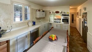A kitchen with a long dining table, cabinets, and a window. - Nice home in La Roque-sur-Pernes (La Roque-sur-Pernes)