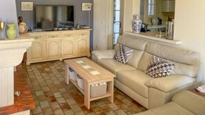 A living room with a beige sofa, a wooden coffee table, and a TV on a cabinet. - Nice home in La Roque-sur-Pernes (La Roque-sur-Pernes)