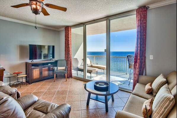 A living room with a television, sofa, and a balcony with a view of the ocean. - *Gulf-Front at Palazzo! *Fall Specials! (Panama City Beach)