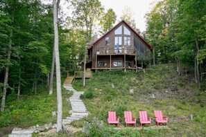 A cabin with a wooden exterior, a deck, and a staircase leading to the entrance. - Stylish and Cozy Cabin on the Red Cedar Chain overlooking quiet bay (Birchwood)