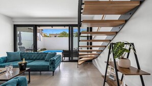 Uma sala de estar moderna com um sofá verde-água, uma mesa de jantar e uma escada com degraus de madeira.