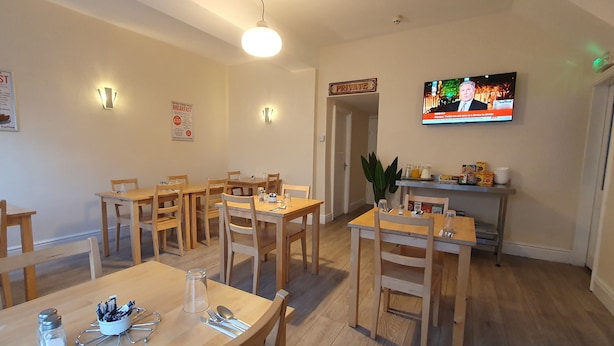 Un comedor con mesas y sillas de madera, un televisor montado en la pared y un letrero que indica una zona de comedor privada.