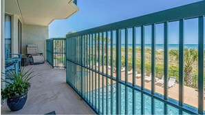 Un balcon avec vue sur l’océan, une piscine et un espace salon extérieur.