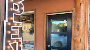 A wooden exterior with a black door and a neon 'OPEN' sign. - Jackalope Loft in Downtown Custer, Sleeps 6 (Custer)