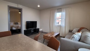 A modern living room with a flat-screen TV, a dining table, and a sofa. - Jackalope Loft in Downtown Custer, Sleeps 6 (Custer)