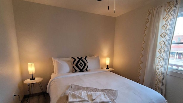 A neatly made bed with white linens, two bedside lamps, and a patterned pillow. - Jackalope Loft in Downtown Custer, Sleeps 6 (Custer)