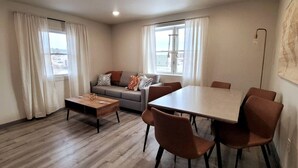 A modern living room with a sofa, coffee table, and dining table with chairs. - Jackalope Loft in Downtown Custer, Sleeps 6 (Custer)