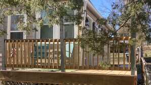 A wooden deck with a lattice railing, a wooden bench, and a flamingo statue.