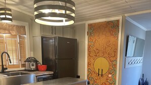 A modern kitchen with a central island, stainless steel appliances, and a wooden backsplash.