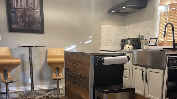 A modern kitchen with a wooden island, stainless steel appliances, and pendant lighting.