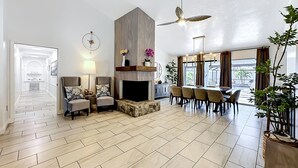 A spacious living area with a fireplace, seating, and a dining table. - Palma Sola Getaway | Private Pool + Games (Bradenton)
