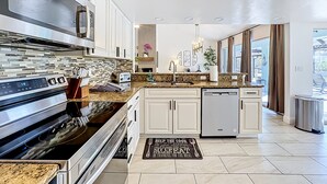 A modern kitchen with stainless steel appliances, white cabinetry, and a granite countertop. - Palma Sola Getaway | Private Pool + Games (Bradenton)