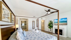 A bedroom with a four-poster bed, a fireplace, a TV, and a view of the beach. - Palma Sola Getaway | Private Pool + Games (Bradenton)