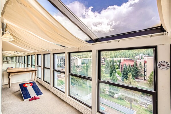 Una habitació amb grans finestres, una taula de fusta i vista a una zona residencial.