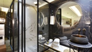 Een moderne badkamer met een marmeren wastafelmeubel, een grote spiegel en een bad.