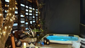 Een gezellig buitenterrein met een jacuzzi, houten meubels en lichtjes.