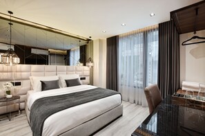 A modern hotel room with a large bed, a glass table, and a mirror above the bed. - Luxury 8BR Villa with Rooftop and Jacuzzis on Lleras Park (Medellín)