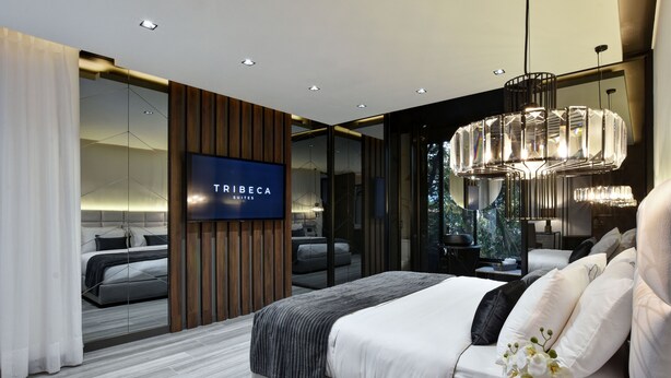 Een moderne slaapkamer met een groot bed, een aan de muur bevestigde televisie en uitzicht op het landschap door een glazen deur.