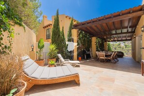 A patio with lounge chairs, a dining table, and potted plants.