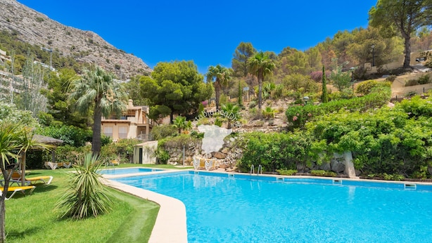 Piscina com água azul cristalina, rodeada por grama verde e árvores.