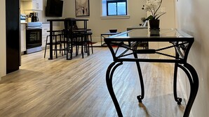 A modern kitchen with white cabinets, a dining area with a glass table, and a large window providing natural light. - Two bedroom suite - great for visiting family, weddings, or Stratford Festival (St. Marys)