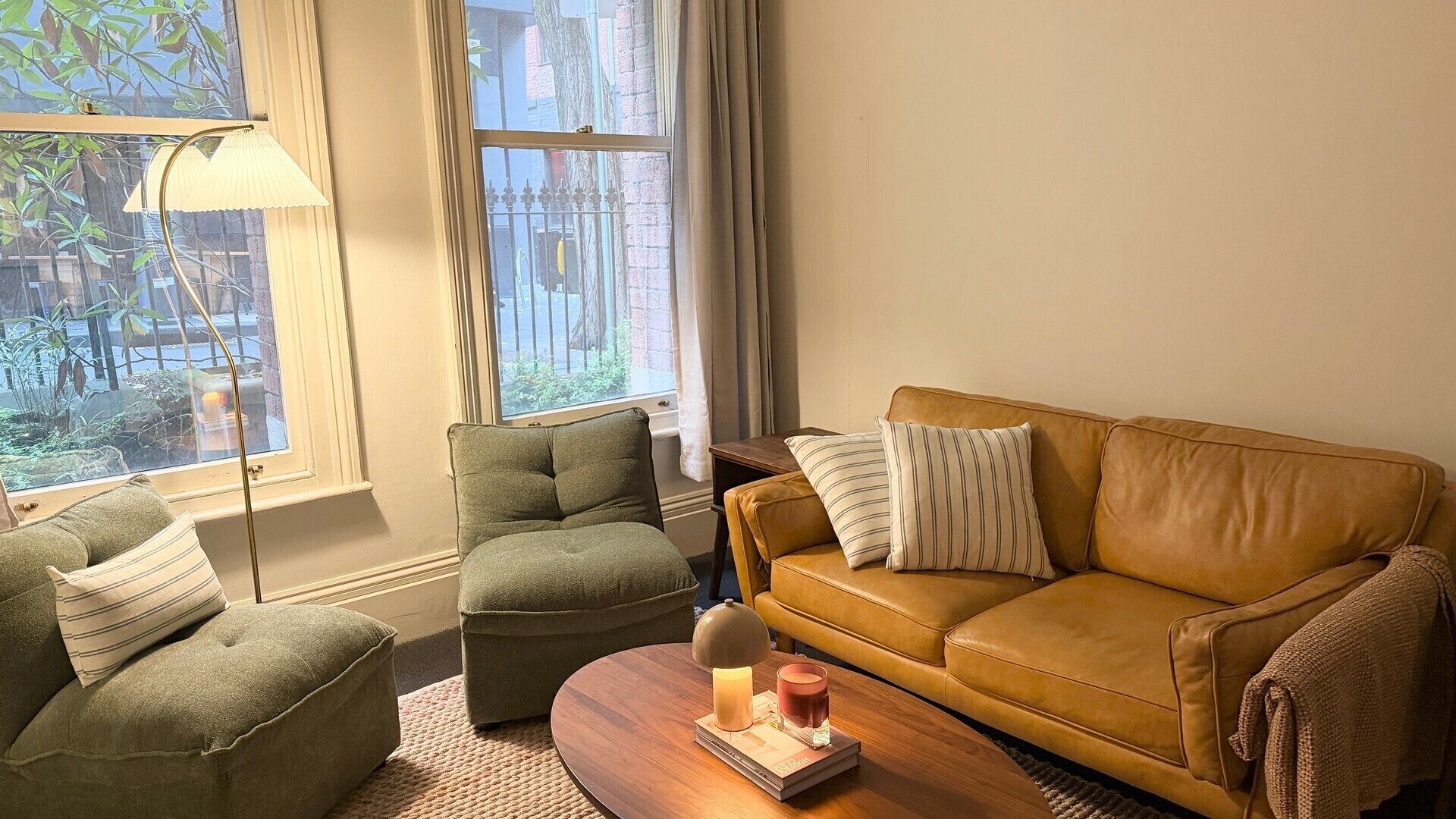 A living room with a brown leather sofa, two armchairs, a wooden coffee table, and a floor lamp.